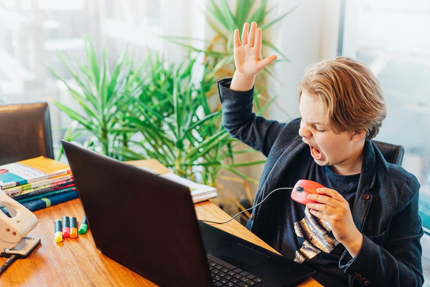 Angry boy sitting at desk with laptop